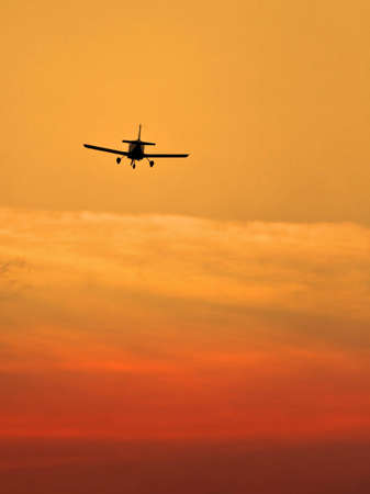 Sunset scene with silhouette of a landing planeの写真素材