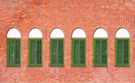 Old brick wall with six green windowsの写真素材
