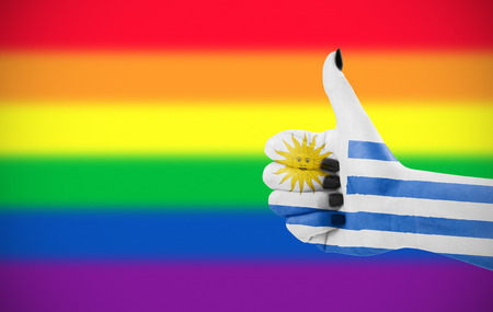 Concept photo - Positive attitude of Uruguay for LGBT community. Hand against rainbow flag. Focus set on hand.の写真素材