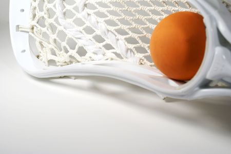 a white lacrosse stick head and an orange ballの写真素材