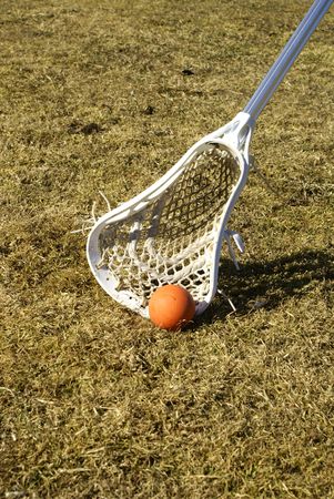 a white lacrosse stick scooping the ball off the groundの写真素材
