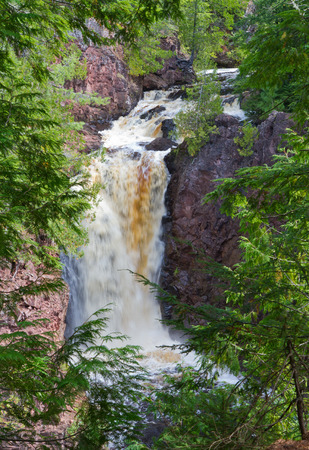 Wilderness waterfall framed by trees.の写真素材