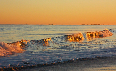 Crashing waves illuminated by the setting sun.の写真素材
