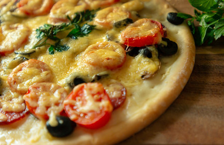Homemade pizza with pepperoni, tomatoes, mozzarella and Basil, edible, on a wooden table with copy space for your text.の写真素材