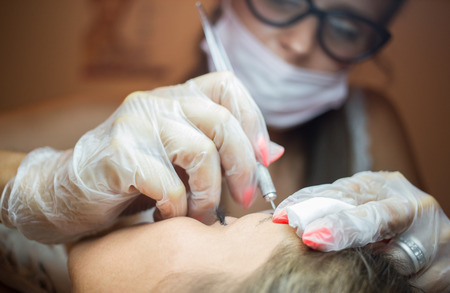 Beautiful young woman lying on her back at a beauty salon getting her eyebrows done