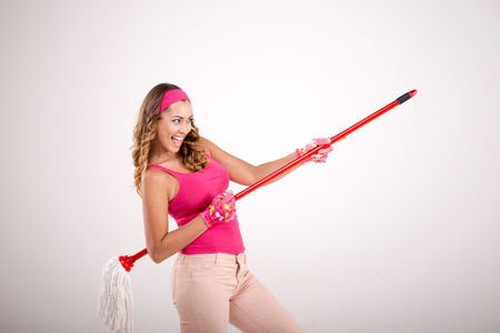 Happy woman cleaning with mop holding it like a guitar while smilingの写真素材