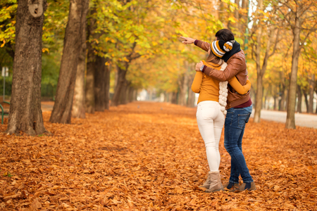 Happy couple walking in a park looking at something and pointingの写真素材