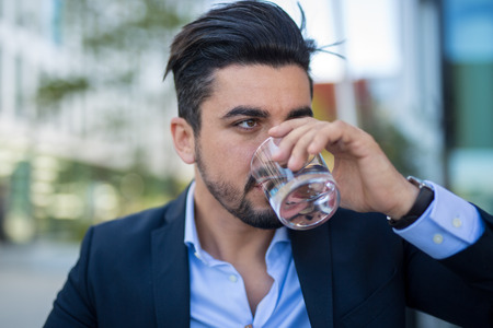 Handsome young businessman drinking water on break daytime