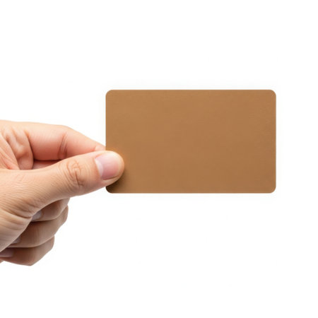A hand is holding a rectangular, brown card with rounded corners. The card is blank and has a smooth surface. The background is plain white, suggesting a product or business card presentation.の素材