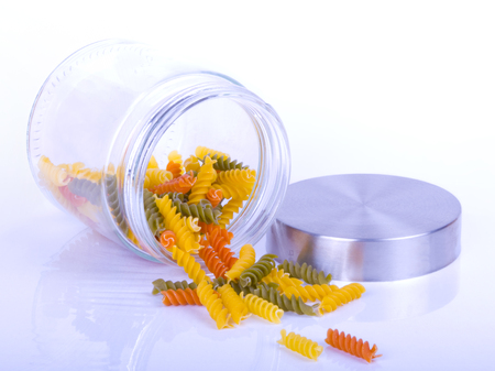 Close up of colorful rotini pasta in a glass jar isolated on white backgroundの写真素材