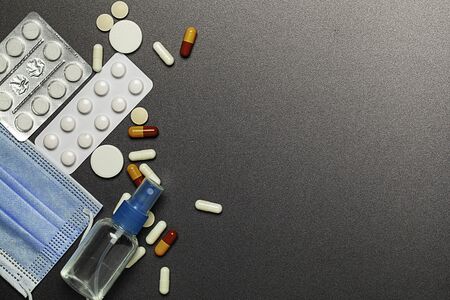 Medical surgical mask, sanitizer gel, lab gloves, pills and tablets  lying on the table. Virus protection equipment.の写真素材