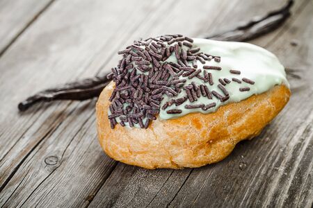 French pastry filled with vanilla cream, glaze with mint and chocolate chips  on old wooden table