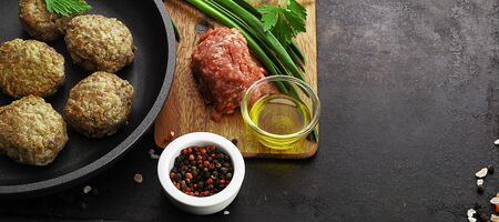cutlets on pan, forcemeat and spices on board over old rustic background