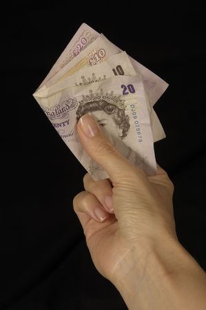 female hand holding out money to be taken, isolated against a black backgroundの写真素材