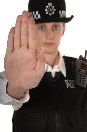 Uniformed UK female police officer with hand up showing stop isolated on white focus on handの写真素材