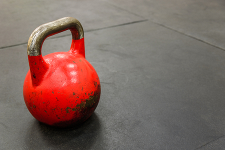 Close-up of red kettlebell on black gym floorの写真素材