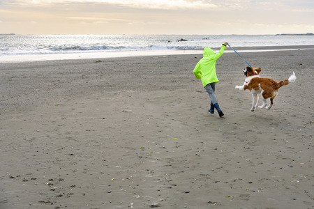 Kid running with dog on the beach after the stormの写真素材