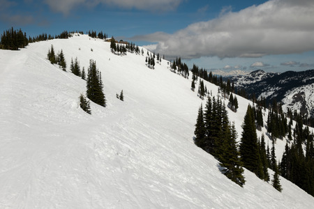 Top of an alpine ski area on a cloudy day with tracks in the snowの写真素材