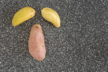 Fingerling potatoes on a cutting board in the shape of a faceの写真素材