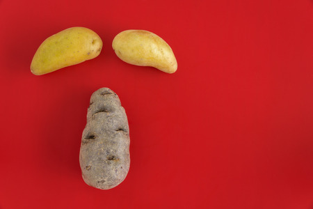 Fingerling potatoes on a red cutting board in the shape of a faceの写真素材