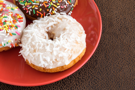 Three frosted cake donuts with colorful sprinklesの写真素材