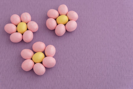 Candy coated Easter eggs in a flower pattern on a purple backgroundの写真素材