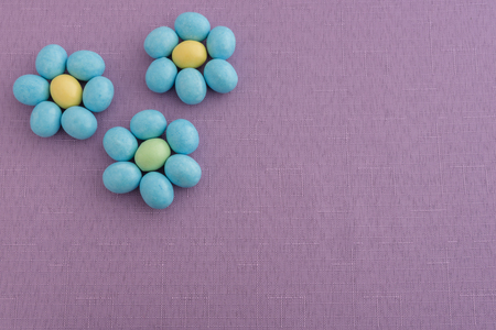 Candy coated Easter eggs in a flower pattern on a purple backgroundの写真素材