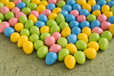 Yellow, pink, blue, and green Easter candy on a green backgroundの写真素材