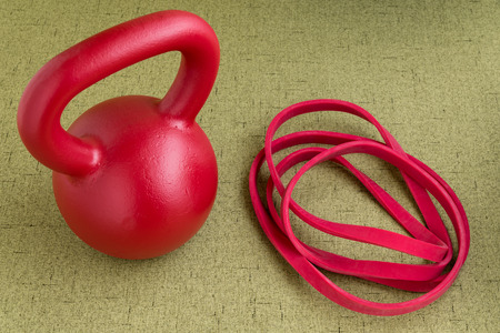 Red kettle bell and red resistance band on a light green backgroundの写真素材