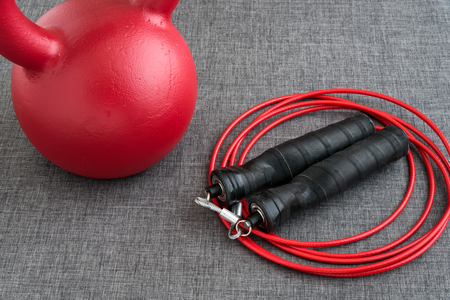 Red kettle bell and red jump rope on a gray backgroundの写真素材
