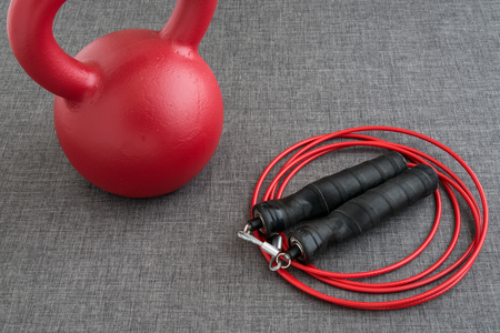 Red kettle bell and red jump rope on a gray backgroundの写真素材
