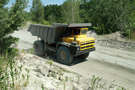 Yellow dump truck driving on a road in a stone quarryの写真素材