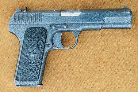 Soviet Tokarev TT pistol on canvas covered with rain dropsのeditorial素材