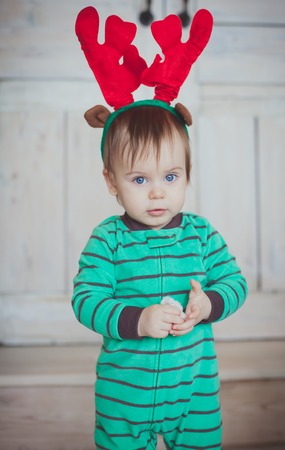 Funny boy with christmas deer horns stay in green clothesの写真素材