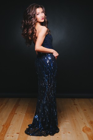 Young beautiful curly women in glitter dress on dark background. Fashion. Concept celebration. Dark backgroundの写真素材