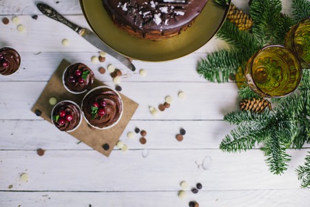 Dark chocolate cake with cookies and cupcakes berries on white wooden background. Flat layの写真素材