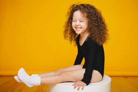 Funny curly little girl laugh in studio on orange backgroundの写真素材