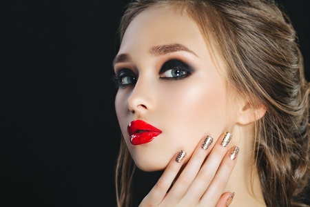 Beauty Woman with Perfect Makeup. Beautiful Professional Holiday Make-up. Red Lips and Nails, perfect eyebrows. Beauty Girls Face isolated on dark background. Isolatedの写真素材