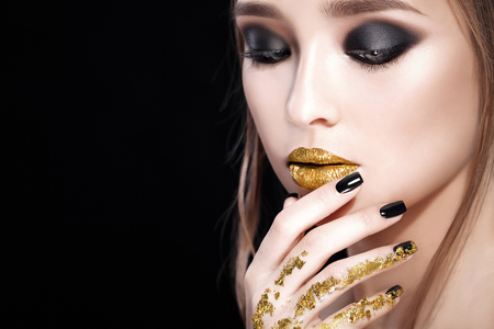 Beauty Woman Portrait. Professional Makeup and Manicure with gold foil and glitter, smokey eyes. Black colors. Studioの写真素材
