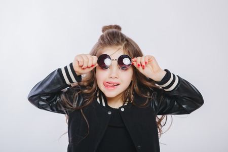 Portrait of little hipster girl in sunglasses, showing tongue. Studioの写真素材