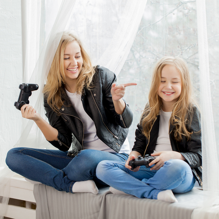 Family games. Mother and daughter play on conlsole togetherの写真素材