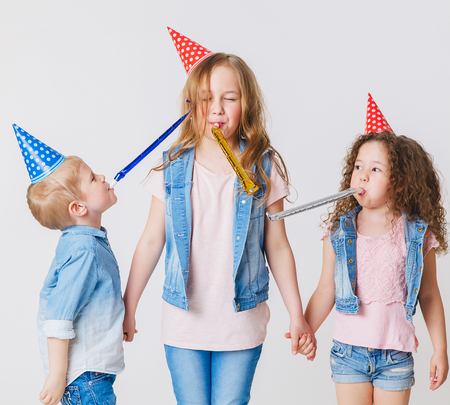 Pretty kids on birthday party having fun in jeans clothes and festive cap.の写真素材