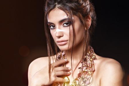 Portrait of beautiful woman with sensitive sexy view, gold nails design and jewelery with natural stones. Ethnics. Studioの写真素材