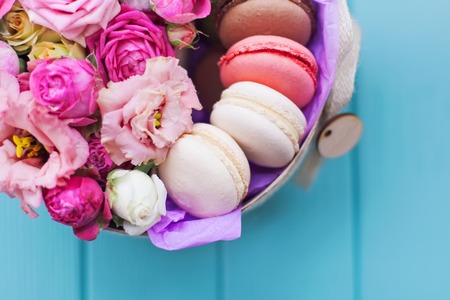 Perfect present, flower composition with macaroons in craft box on blue wooden backgroundの写真素材