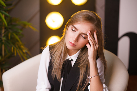 Portrait of beautiful tired student girl. Sitting in the office. Plants on the backgroundの写真素材