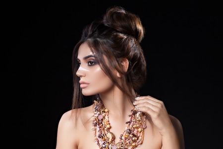 Portrait of beautiful woman with sensitive sexy view, gold nails design and jewelery with natural stones. Ethnics. Studioの写真素材