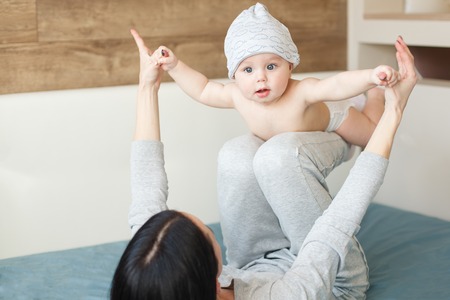 Baby boy in funny cap doing exercises with his mother. Indoorの写真素材