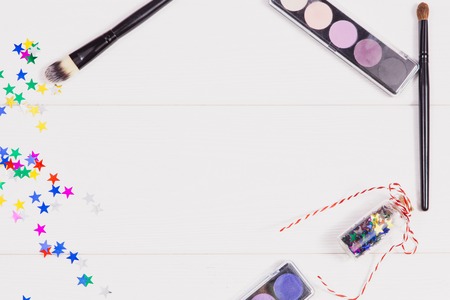 Flat lay with visage brush and eye shadows. Accessories and decorations on the white wooden background. Concept holiday make-upの写真素材