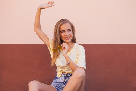 Portrait of beauty fashion smiling young women with yellow sunglasses dancing and relaxing. Flying hairs. Outdoorの写真素材