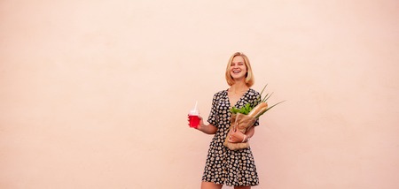 Portrait of young smiling student woman with craft shop bag, with green salad, onion and bread. Concept Healthy food, snackの写真素材